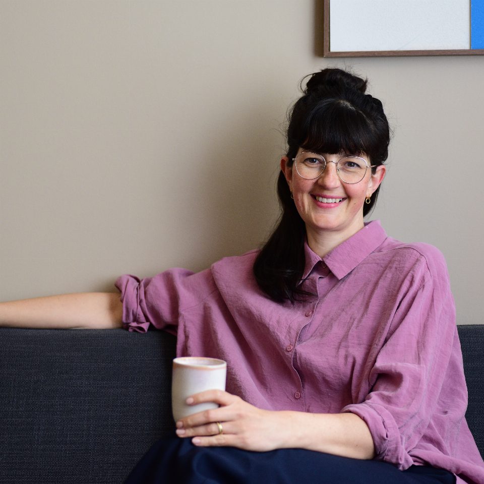 Nora Urgatz mit einer Tasse auf dem Sofa