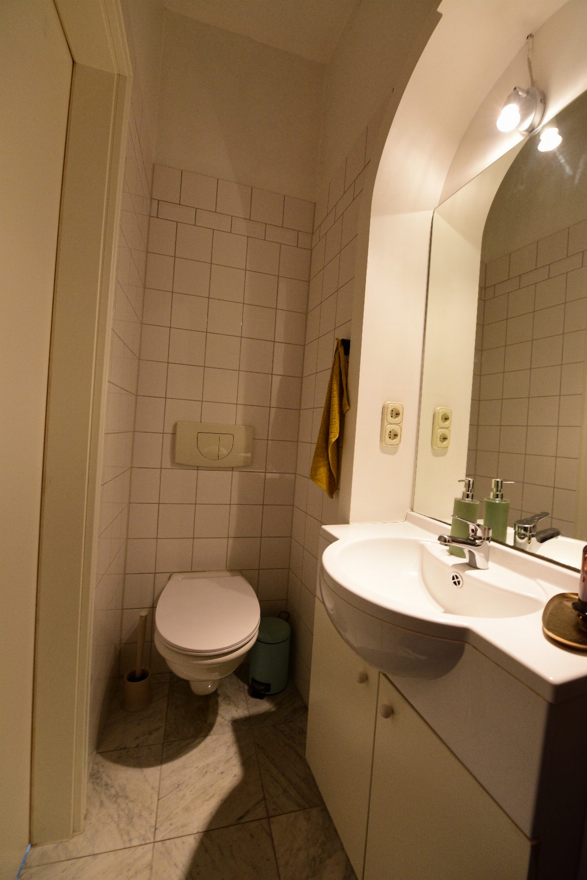 In einem sehr kleinen Badezimmer ist eine wandhängende Toilette zu sehen. Alles ist sehr sauber.